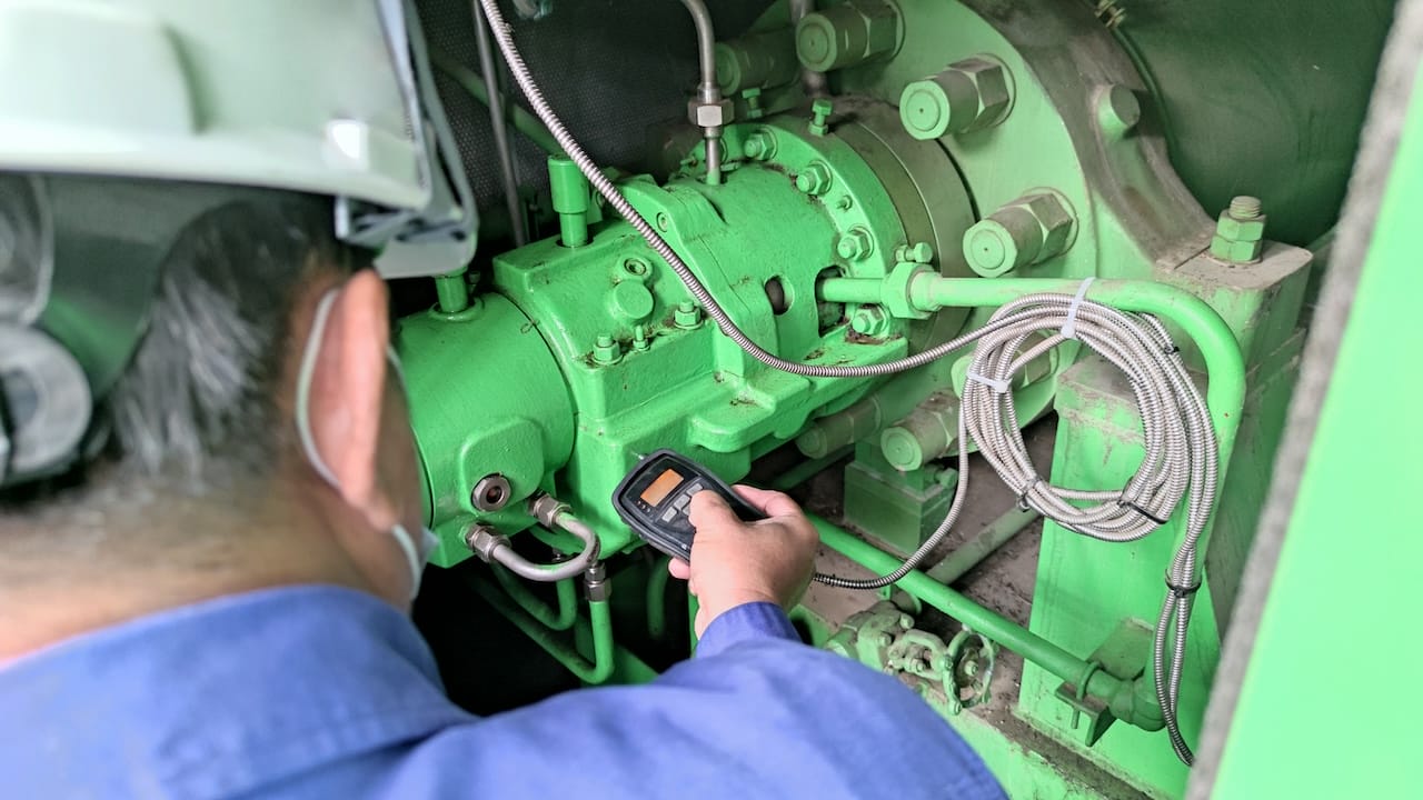 Inspector using a Handheld Vibration Tester (Accelerometer) for checking bearings and overall vibration of motor. Selective focus on inspection area.